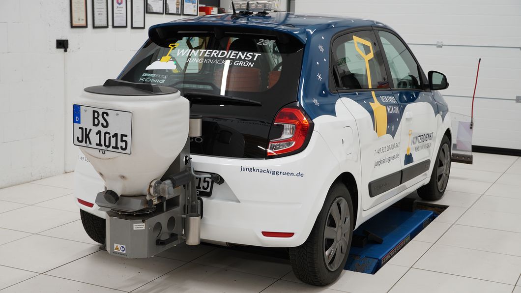 Renault Twingo mit Winterdienst-Beschriftung und Streugerät am Heck, steht in einer Werkstatt