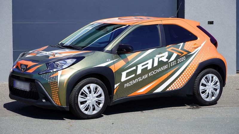 Folierter Toyota mit orange-grünem Grafikdesign und großflächiger Fahrzeugbeschriftung